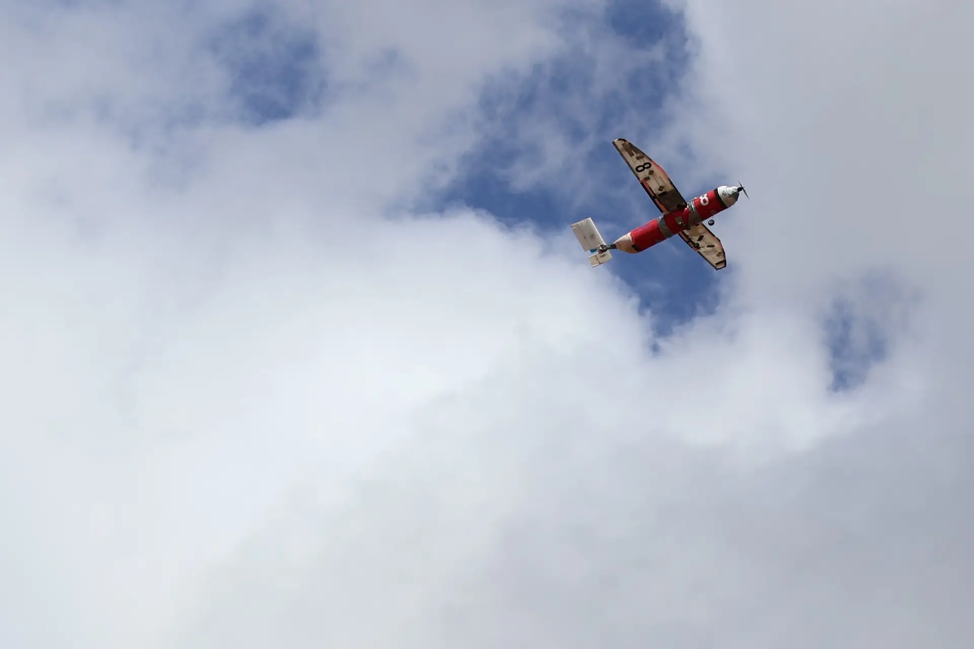 El Insomnio en vuelo sobre un cielo con nubes, con el fuselaje rojo y el número 8 en el ala